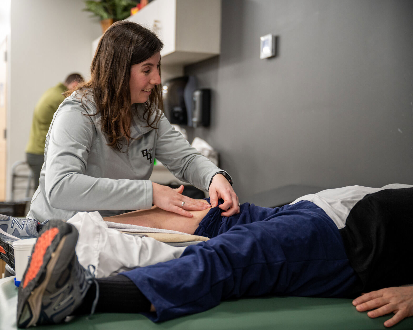 A Physical Therapist happily works on a knee patient.