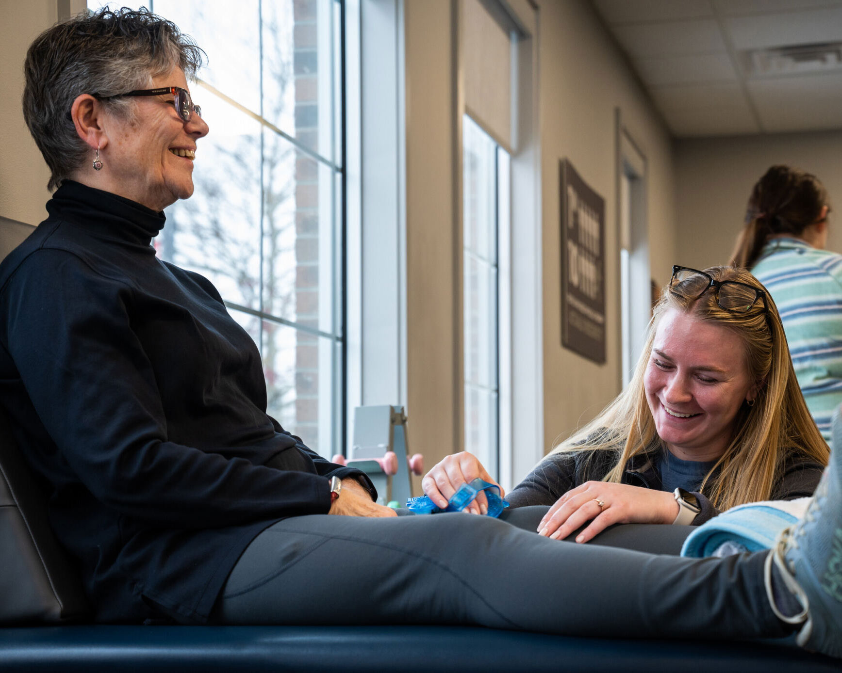 A Physical Therapist happily works on a knee patient.