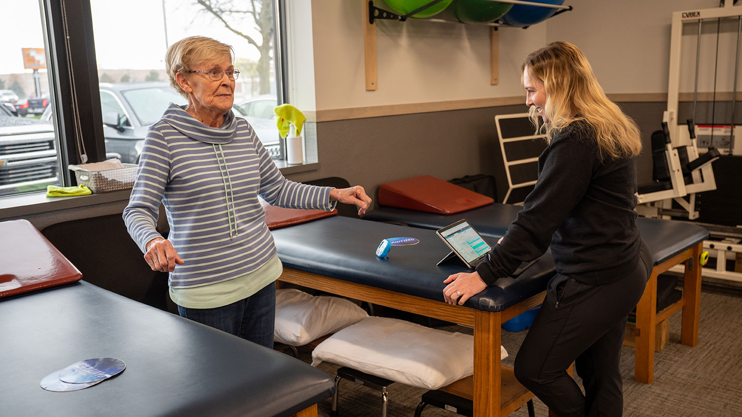 A certified occupational therapy assistant smiles as she converses with her patient.