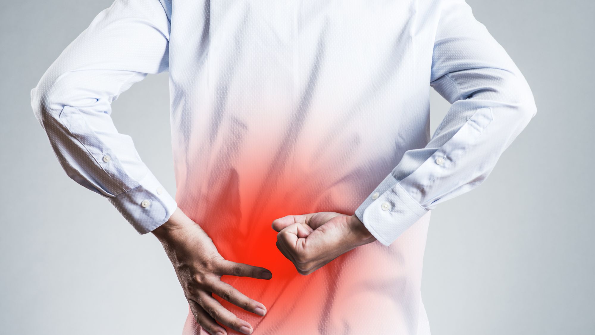 Image of a man in a white shirt with low back pain indicated in red.