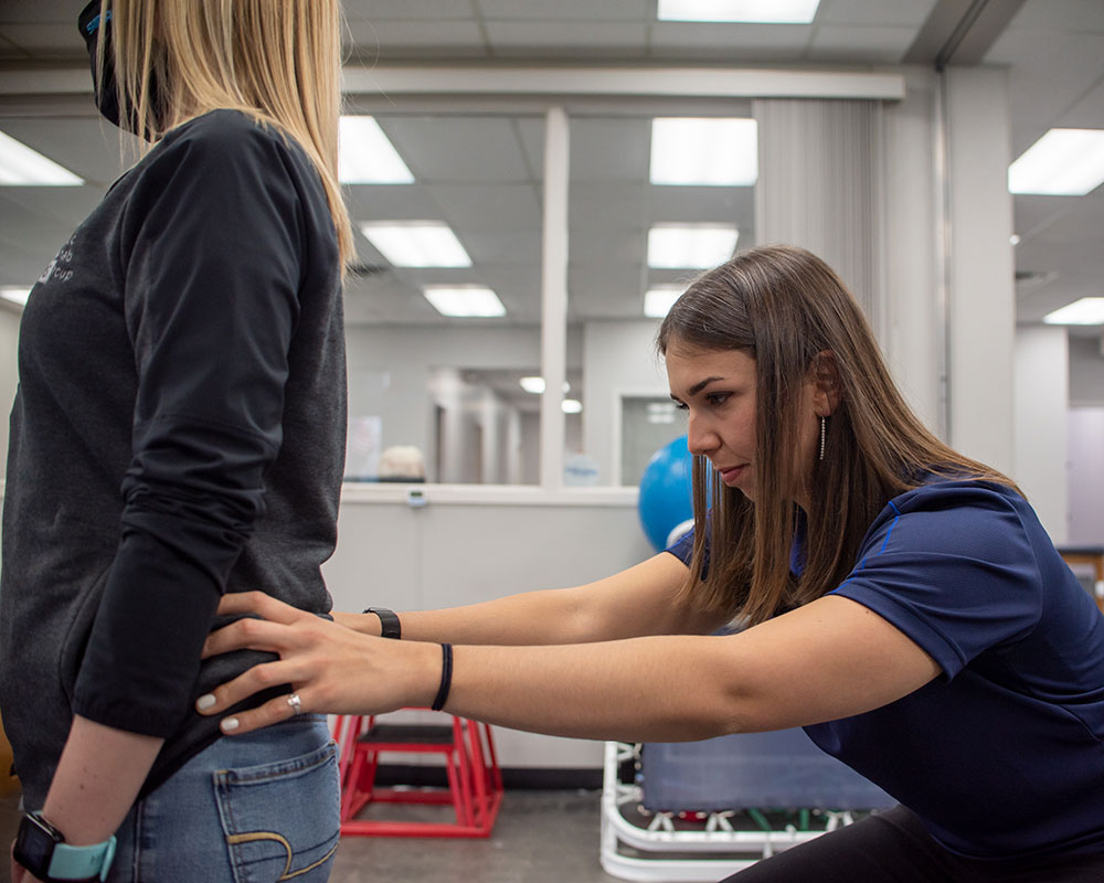A Physical Therapist treats and injury on her patient's back, focusing intensely on the area.