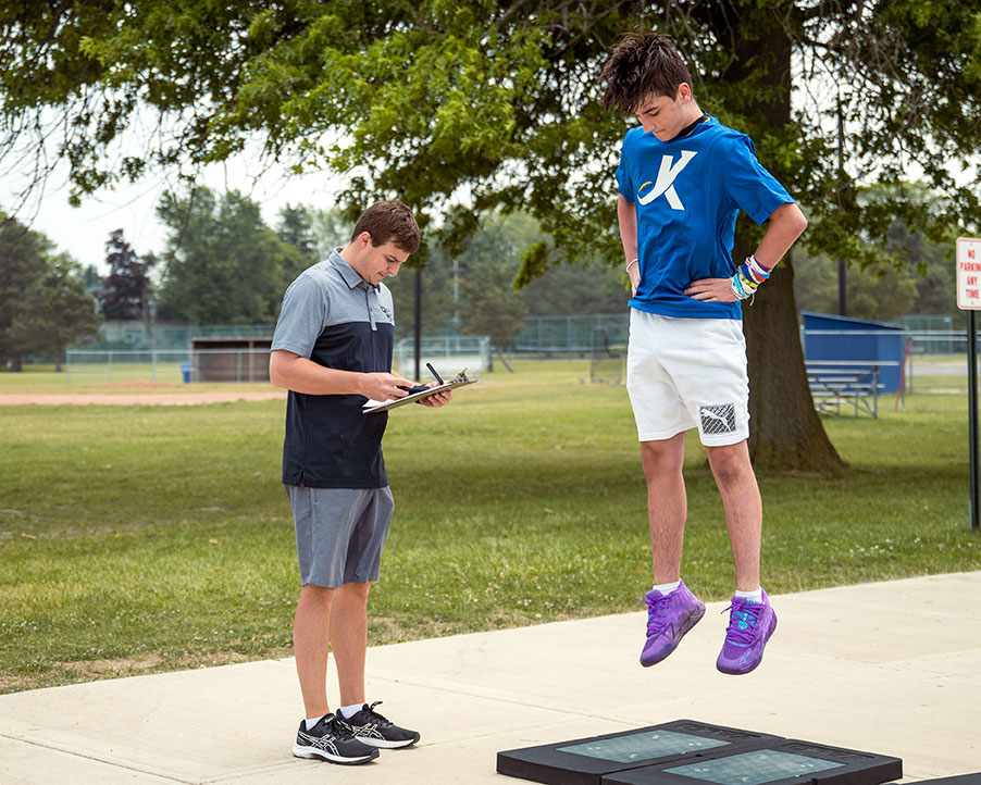 A physical therapist watches as a young athlete jumps on a ForceDecks plate.