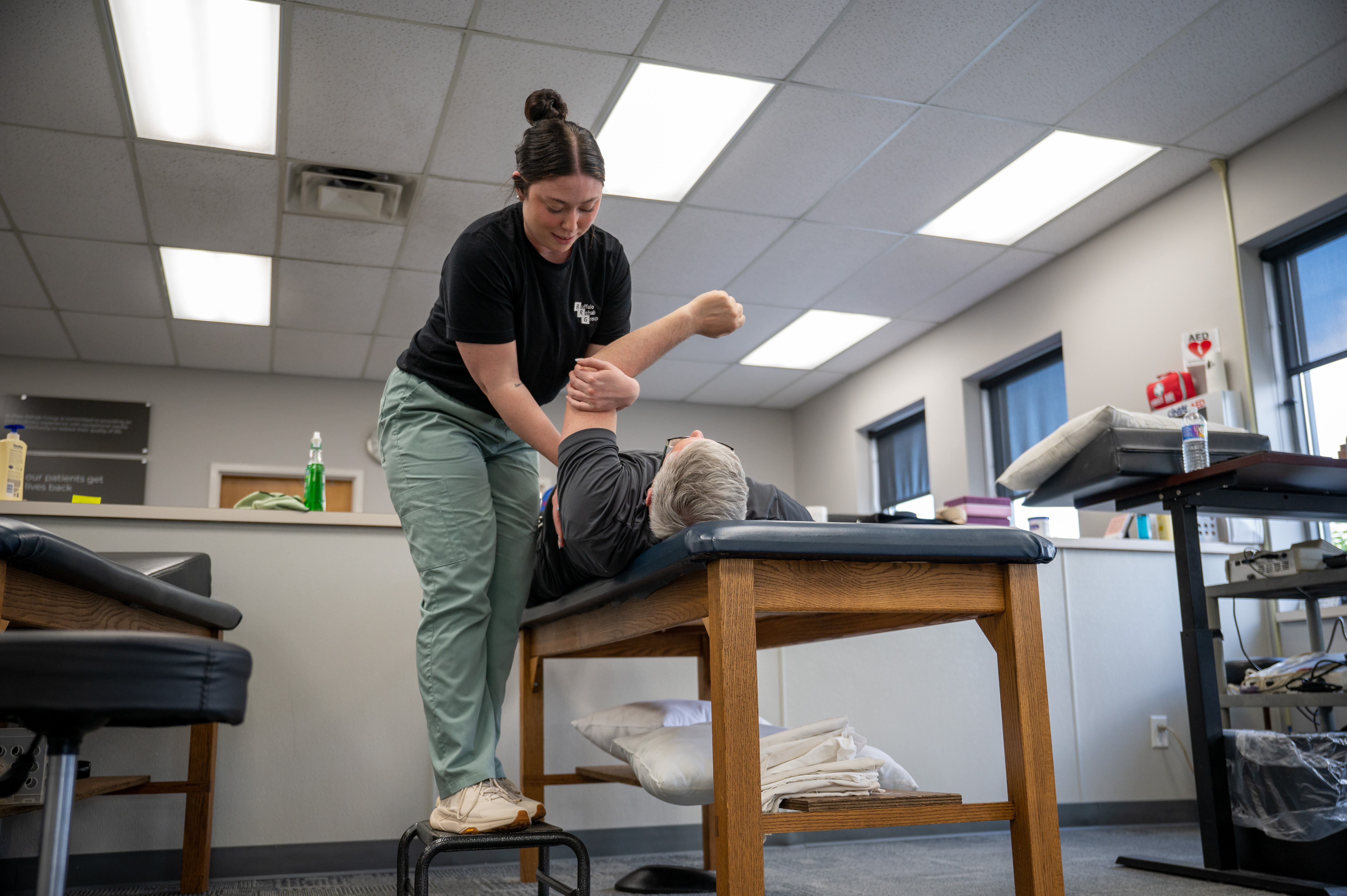 A Physical Therapist happily works on a shoulder patient.