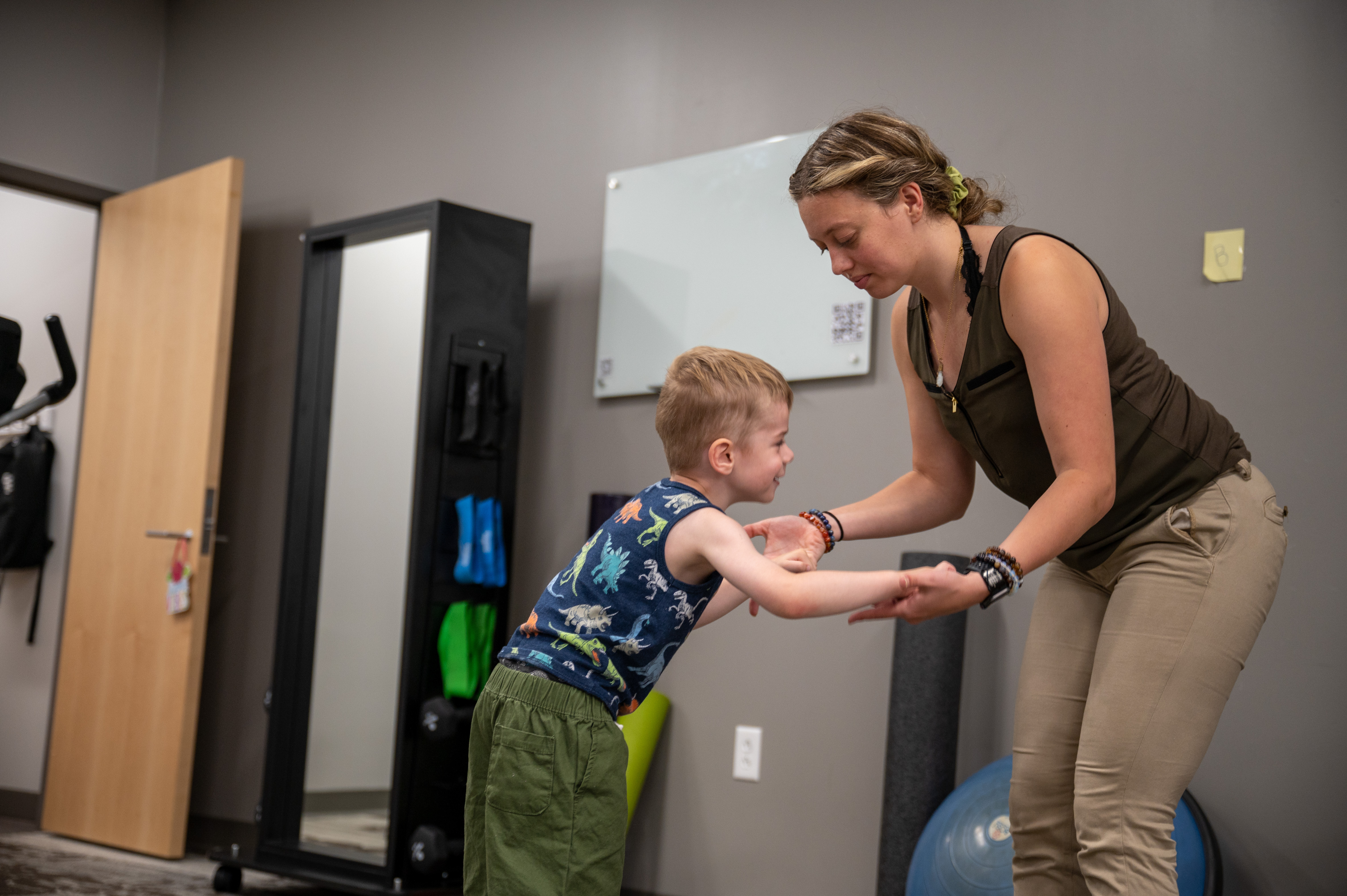 A physical therapist helps her patient balance on a yoga ball.