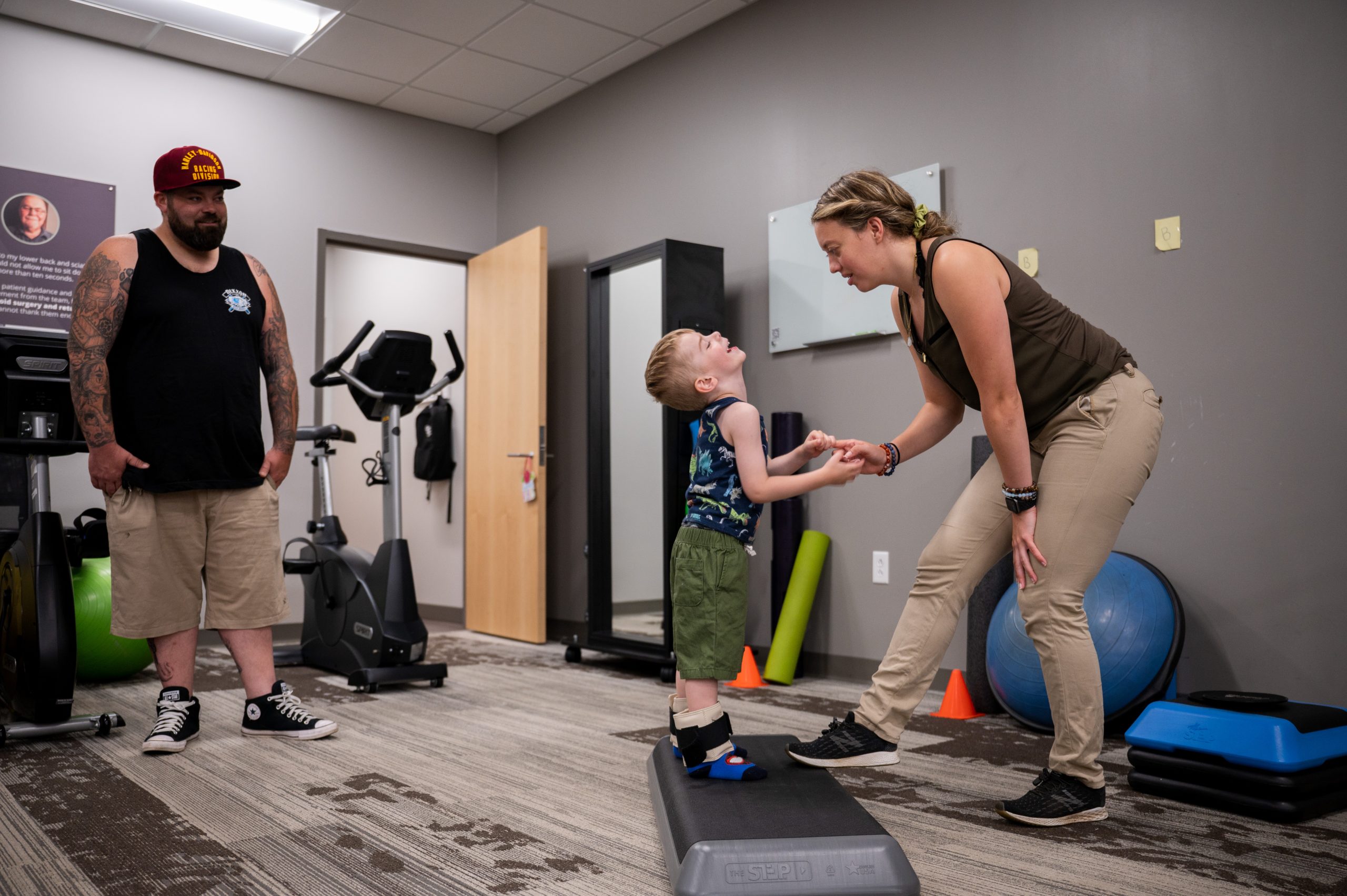 A Physical Therapist converses with her patient as her patient sits upon a yoga ball.